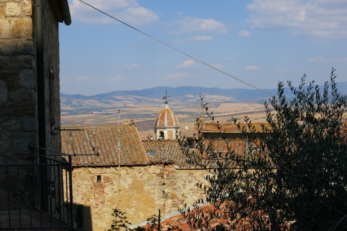 Castiglione d’Orcia -kylä Toscanassa, kirkko, kattoja ja peltomaisemaa